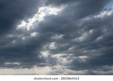 Sky Background. Detail view of a cloudscape with sun's rays piercing through storm clouds