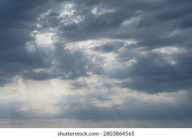 Sky Background. Detail view of a cloudscape with sun's rays piercing through storm clouds