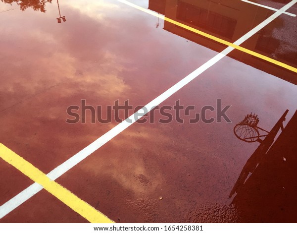 sky and\
basket reflected in a wet basketball\
court