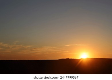 Sky with a Black Mountain Silhouette. Play of Light and Shadow. sun set above horizon line. Sunset above horizon line with sun setting down behind mountains and sun rays. mountains peak. sun beam - Powered by Shutterstock