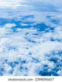 Sky blue background with white clouds, showcasing the beauty of nature. View from airplane window