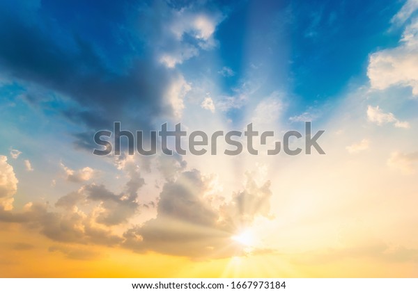 Sky blue and orange light of the sun through the\
clouds in the sky