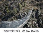 Sky Bridge in Chunkurchak Gorge, Kyrgyzstan. Suspension excursion bridge over gorge. Sightseeing holiday tour. Crossing between two mountains. Dangerous footbridge. Hiking trek, pathway, side view