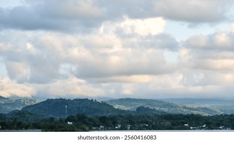 The sky is cloudy and the mountains are in the background. The clouds are white and the mountains are green