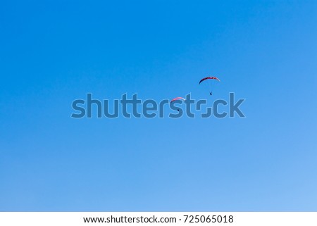 Sky Diving with space in solid blue sky for your text.