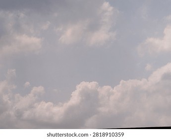 The sky is dominated by a layer of thin clouds at the top and denser clumps of Cumulus clouds below. The cloud colors range from grayish-white to a bright white where they catch the reflected sunlight.