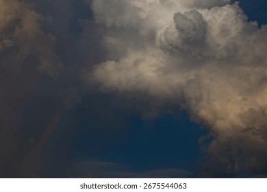 The sky features a dynamic display of clouds, with a partial rainbow adding a touch of color against the dark blue backdrop.