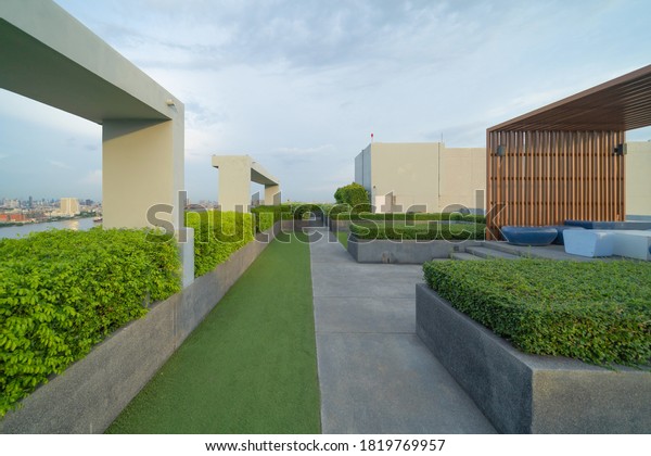 Sky garden on private rooftop of condominium or\
hotel, high rise architecture building with tree, grass field, and\
blue sky.