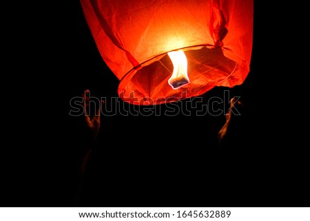 Sky Lantern With Hands In Black Isolated Background