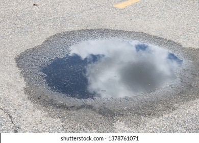  Sky Reflected In A Puddle Of Water On Pavement 