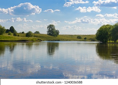 sky reflection with clouds in a lake with green shores on a summer day