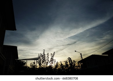 A sky in the time of the sunset with a dark shadow detail of village and trees.