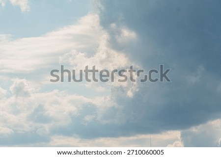 A sky with various cloud formations, dominated by dark cumulonimbus clouds contrasting against lighter cirrus and altocumulus Viewed from below, creating a sense of scale and depth No human-made ob