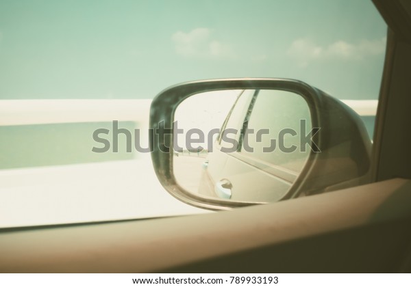 Sky view from car window and side view of black\
car in wing mirror while driving for transportation concept, added\
colour filter effect