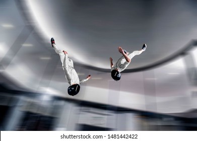 Skydive Australia. Indoor Skydiving In Wind Tunnel. Men Fly In Black Helmet And  White Suit. 