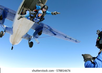 Skydive tandem is jumping out of an airplane. Cameraman is shooting video about it.