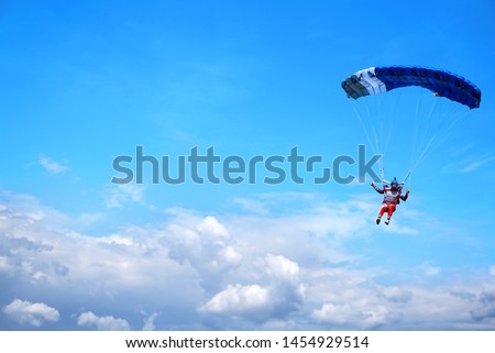 Skydiver with a blue little canopy of a parachute on the background a blue sky and white  clouds, close-up. Skydiver under parachute above the stormy clouds.  USA, Michigan