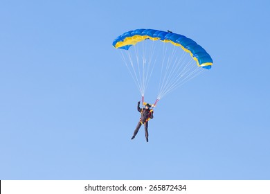 Skydiver on blue and yellow parachute 