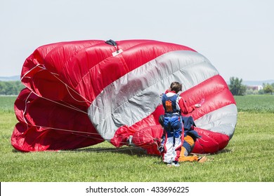Skydiver with red parachute after landing on the ground.