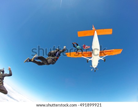 Skydivers jumping from the orange plane