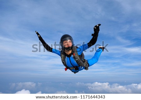 Skydiving. Girl in blue suit is in the sky.