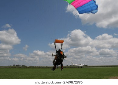 Skydiving – Soaring through a clear blue sky while attached to a colorful parachute