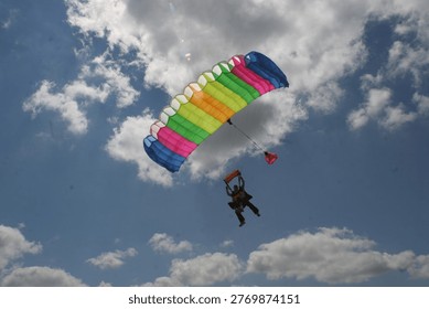 Skydiving – Soaring through a clear blue sky while attached to a colorful parachute