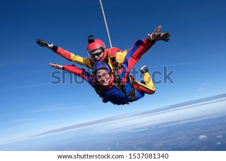 Skydiving. Tandem jump. An instructor introduces a girl to the flight. The happy girl is flying in the sky.