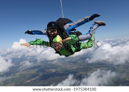 Skydiving. Tandem jump. Pretty woman and her instructor are flying in the sky.