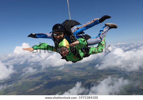 Skydiving. Tandem jump. Pretty woman and her\
instructor are flying in the\
sky.