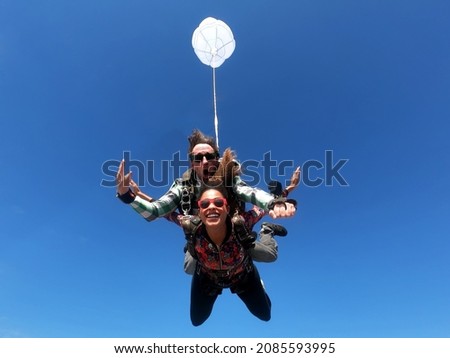 Skydiving tandem parachute jump. Beautiful fashion woman.