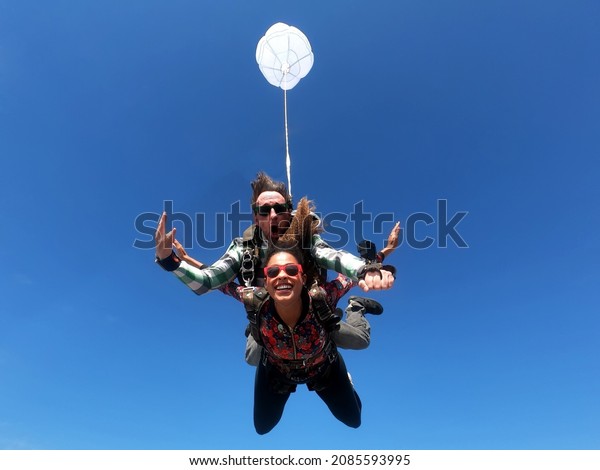 Skydiving\
tandem parachute jump. Beautiful fashion\
woman.