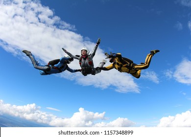 Skydiving. Two instructors are training a skydiver-student to fly.