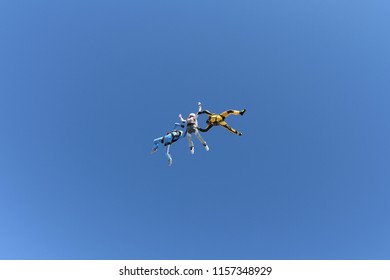 Skydiving. Two instructors are training a skydiver-student to fly.