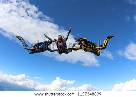Skydiving. Two instructors are training a skydiver-student to fly.