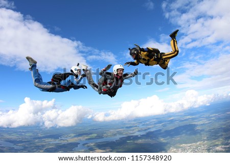 Skydiving. Two instructors are training a skydiver-student to fly.