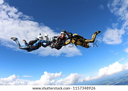 Skydiving. Two instructors are training a skydiver-student to fly.