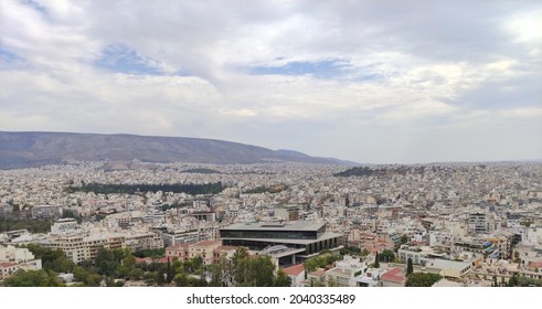The skyline of the city of Athens, as seen from the Akropolis, during a cloudy, summer day. The Akropolis museum is in the middle.