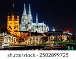 Skyline cityscape in Cologne, Germany. Illuminated, across the river Rhine, Cologne Cathedral stands tall next to the Great St. Martin Church.