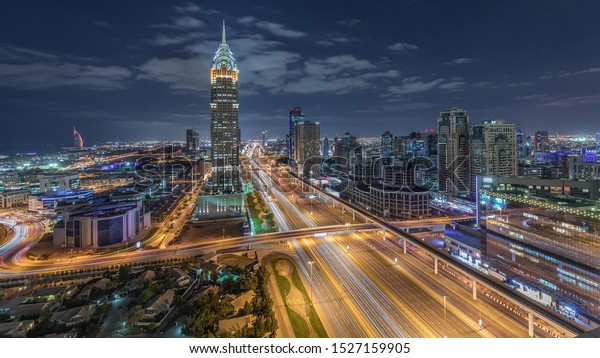 Skyline internet city with crossing\
Sheikh Zayed Road aerial night timelapse. Illuminated skyscrapers\
with traffic on a highway and metro line in\
Dubai