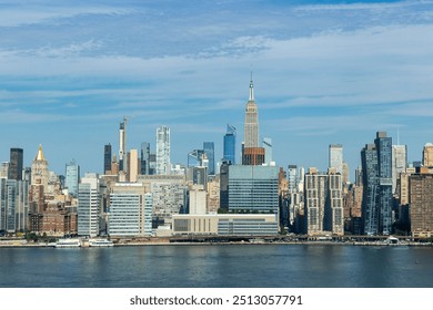 The skyline of New York City showcases a mix of historic and modern skyscrapers, with the iconic Empire State Building prominently rising against a bright blue sky. - Powered by Shutterstock