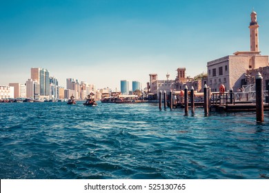 Skyline view of Dubai Creek with traditional boats and piers. Sunny summer day. Famous tourist destination in UAE. Creative color post processing.