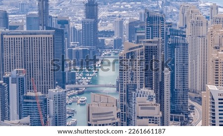 Skyline view of Dubai Marina showing an artificial canal surrounded by skyscrapers along shoreline during all day aerial timelapse with shadows moving fast. Floating yachts and boats. DUBAI, UAE