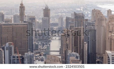 Skyline view of Dubai Marina showing an artificial canal surrounded by skyscrapers along shoreline during all day aerial with shadows moving fast. Floating yachts and boats. DUBAI, UAE