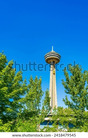 The Skylon Tower stands tall above the lush greenery of Niagara Park, its observation deck promising panoramic views against a vivid blue sky. ON, Canada. High quality photo