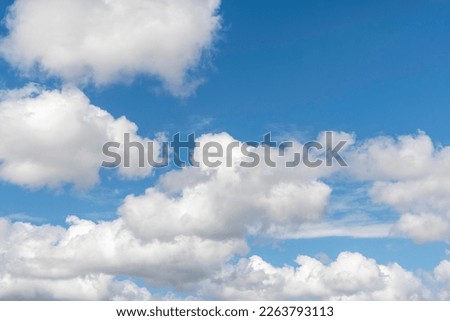 Skyscape background of white clouds set against the soft blue sky in the afternoon light