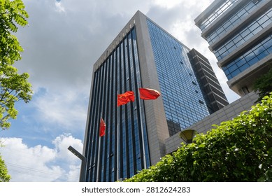 Skyscraper with flags against cloudy sky background.