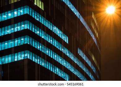 Skyscraper Glowing At Night. Street Lamp In The Corner Of The Image