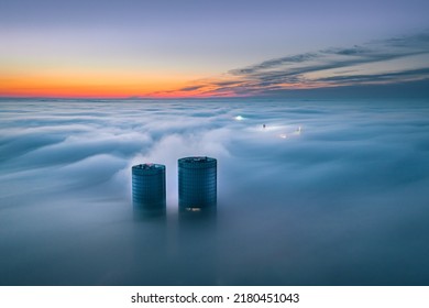 Skyscraper rooftop over the clouds at sunrise. Thick fog covers the Riga city, and warm sunlight over the clouds and church tower. - Shutterstock ID 2180451043