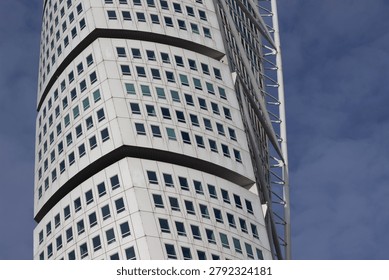 Skyscraper with a unique curved facade and multiple windows, set against a clear blue sky, highlighting modern architectural design in an urban environment
